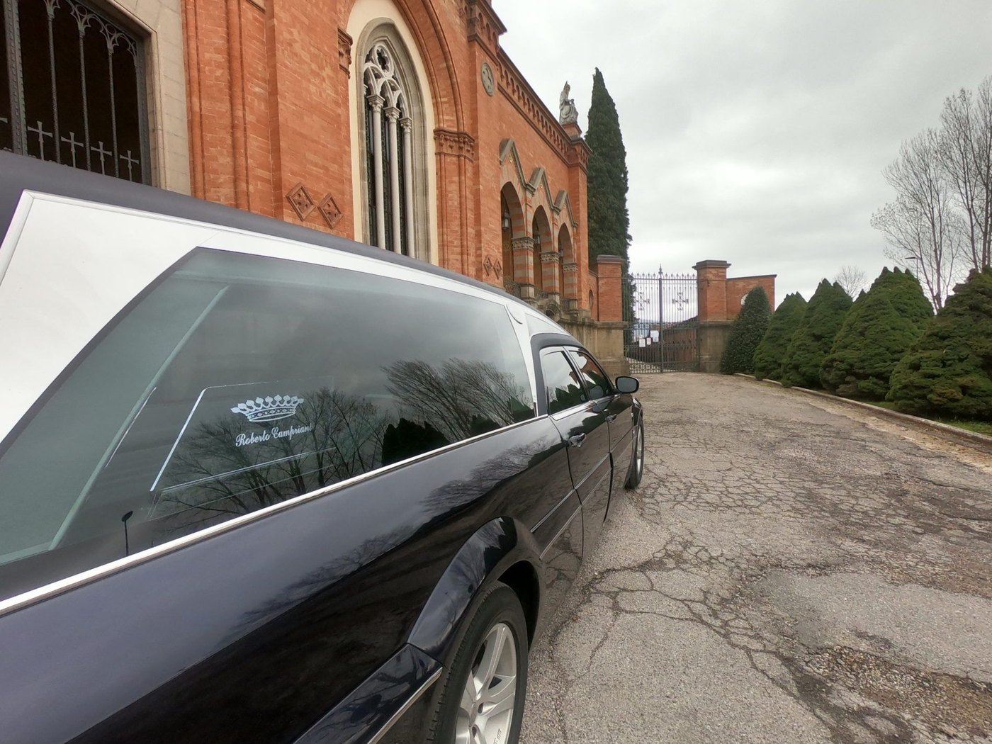 Auto funebre dell'agenzia davanti al cimitero durante una cerimonia